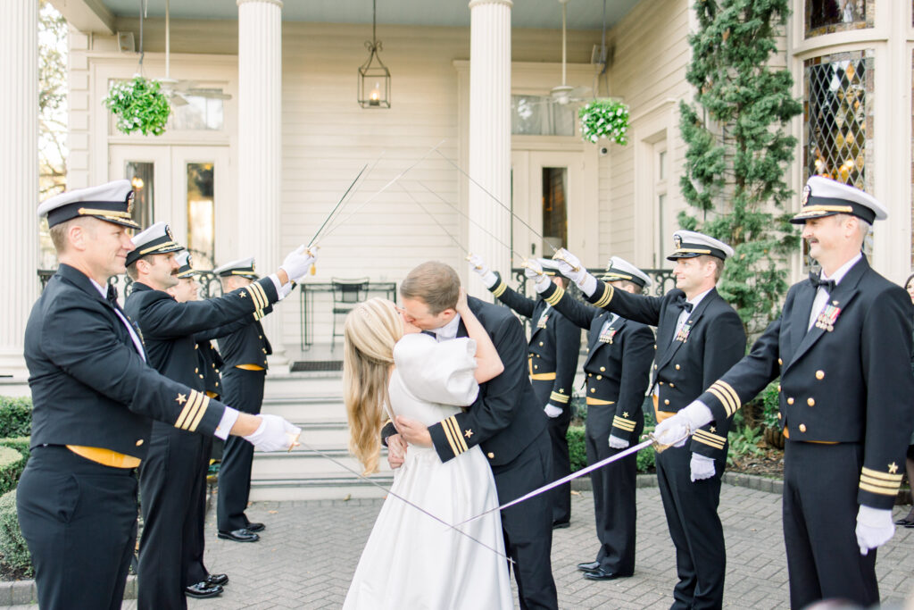 A newly wed couple kiss under a saber arch created by the groom's military peers at their Elms Mansion wedding.
